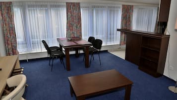 Ein Zimmer mit Holztisch und -stühlen, einem kleinen Schreibtisch und einem Bücherregal.