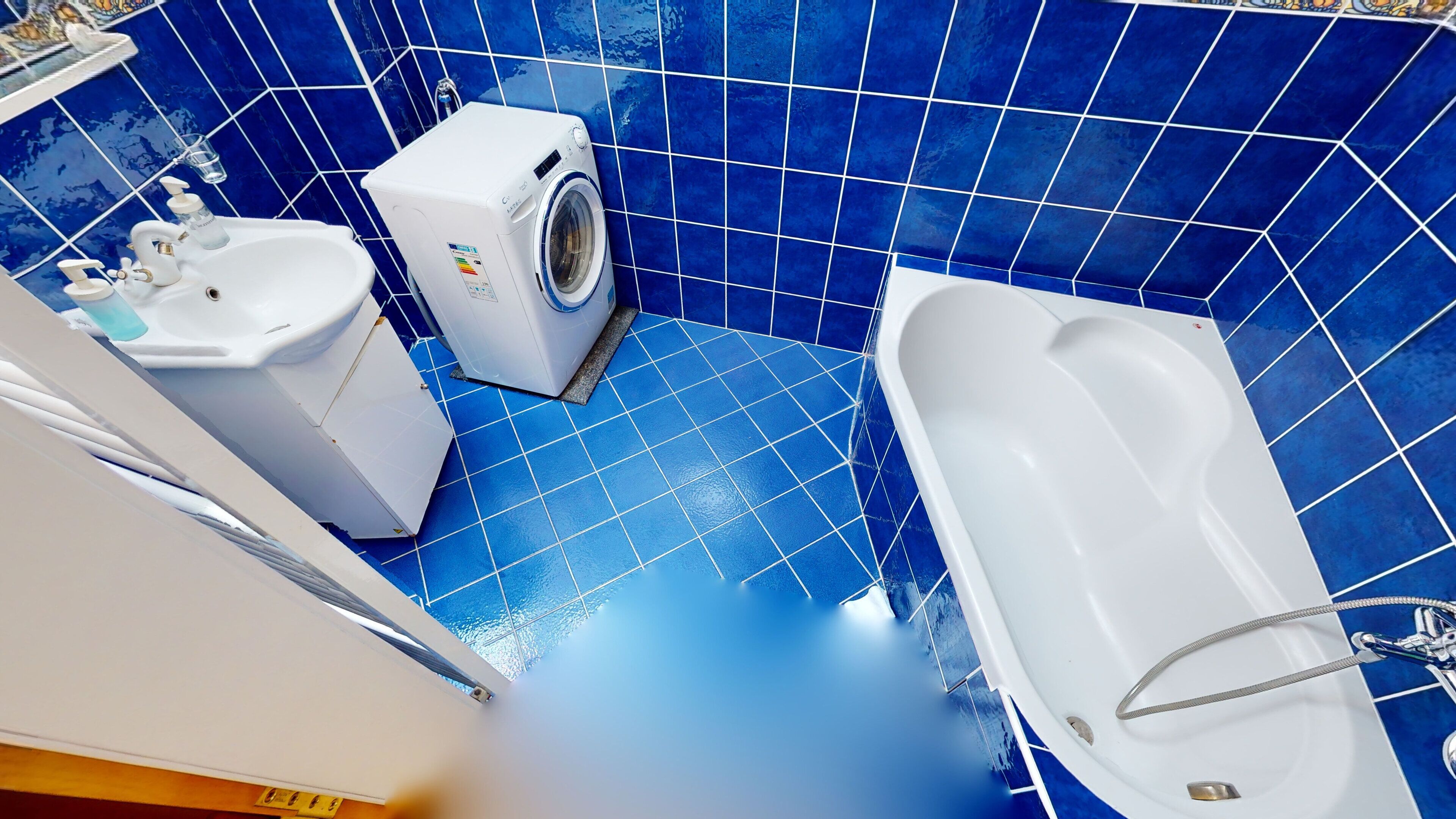 A bathroom with a white bathtub, a washing machine, and a sink.