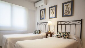A hotel room with two beds, a nightstand with a lamp, and two framed pictures on the wall. - Ocean view condo located in front of the beach with sunny terrace - only families (Playa de Gandía)