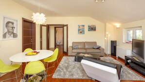 A modern living room with a dining area, a sofa, a TV, and artwork on the walls. - New brand apartment with sea view  (Dubrovnik)
