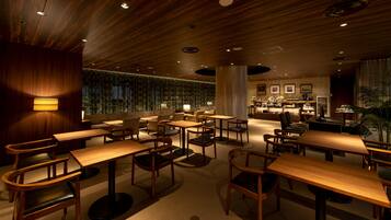 A modern restaurant with wooden tables and chairs, a bar area, and a view of the cityscape.