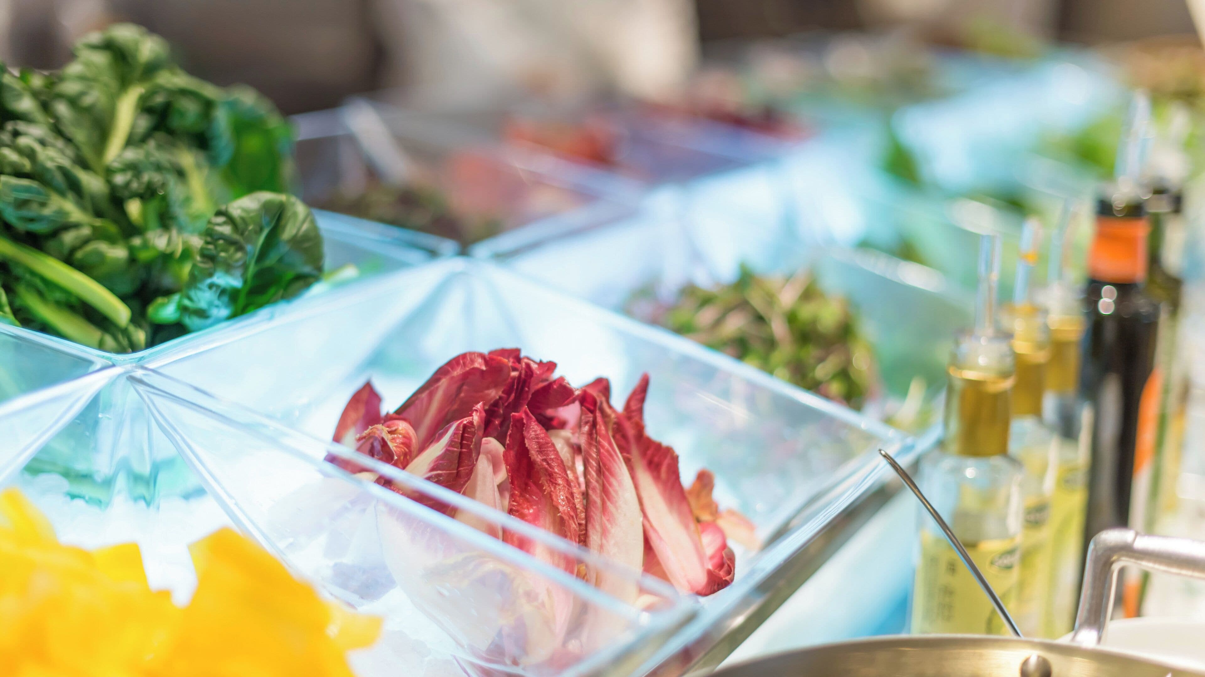 Un buffet de salades proposant une variété de légumes et de condiments.