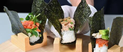 Tres rollos de sushi sobre pedestales de madera.