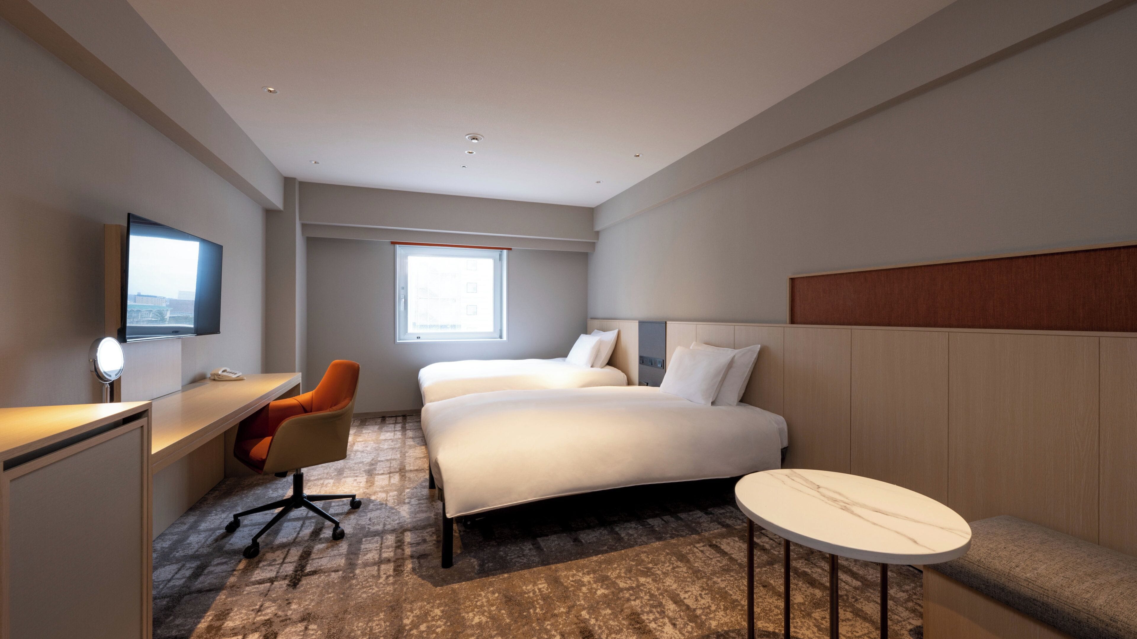 Une chambre d’hôtel équipée d’un lit, d’un bureau, d’une chaise, d’une table ronde et d’un téléviseur.