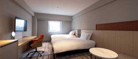 Une chambre d’hôtel équipée d’un lit, d’un bureau, d’une chaise, d’une table ronde et d’un téléviseur.