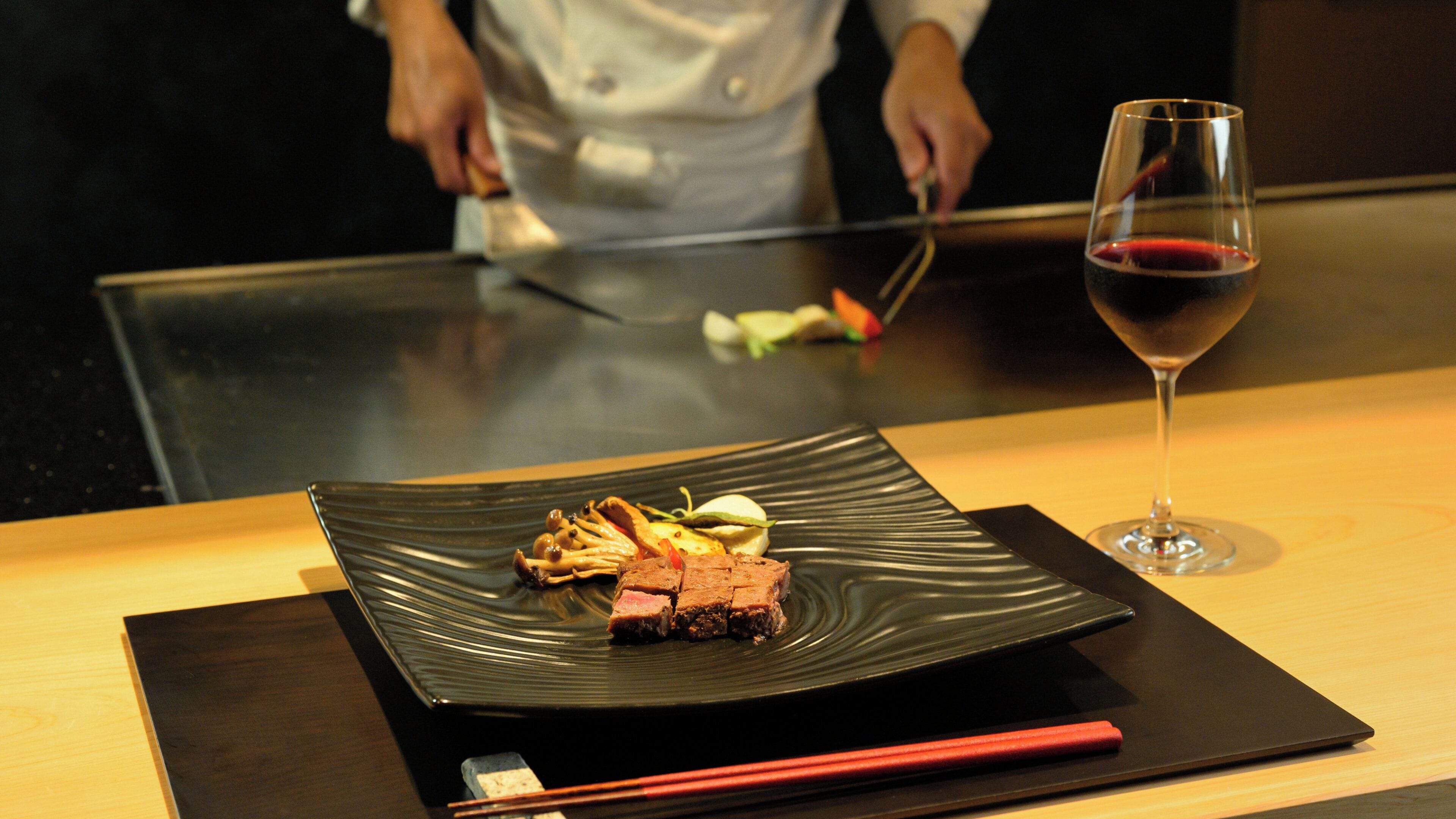 A dining table with a plate of food and a glass of red wine.