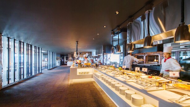 A modern kitchen with chefs preparing food, a buffet line with plates and utensils, and large windows along the corridor. - ANA Crowne Plaza Akita by IHG (Akita)