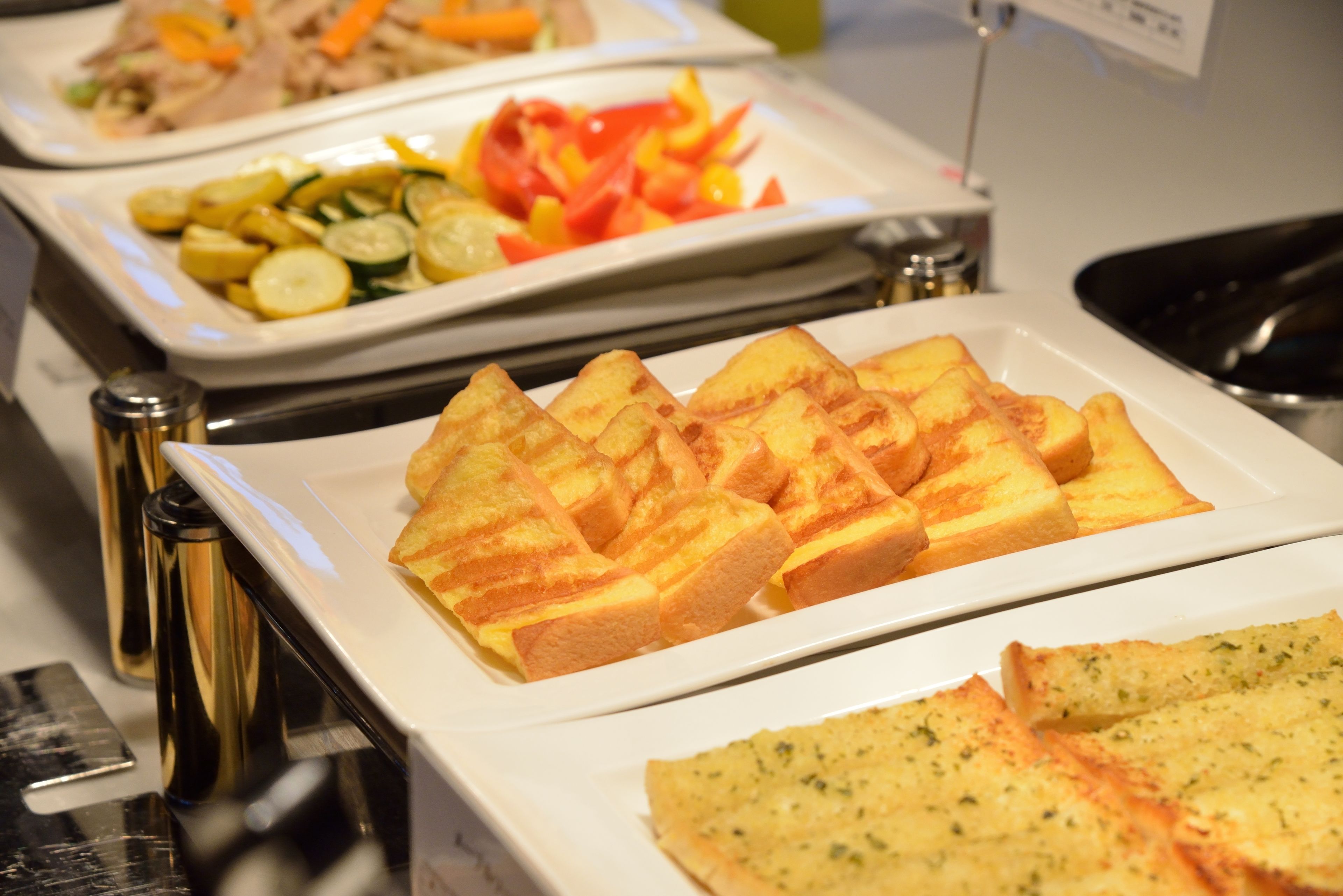 A buffet with various dishes including bread, vegetables, and a salad.