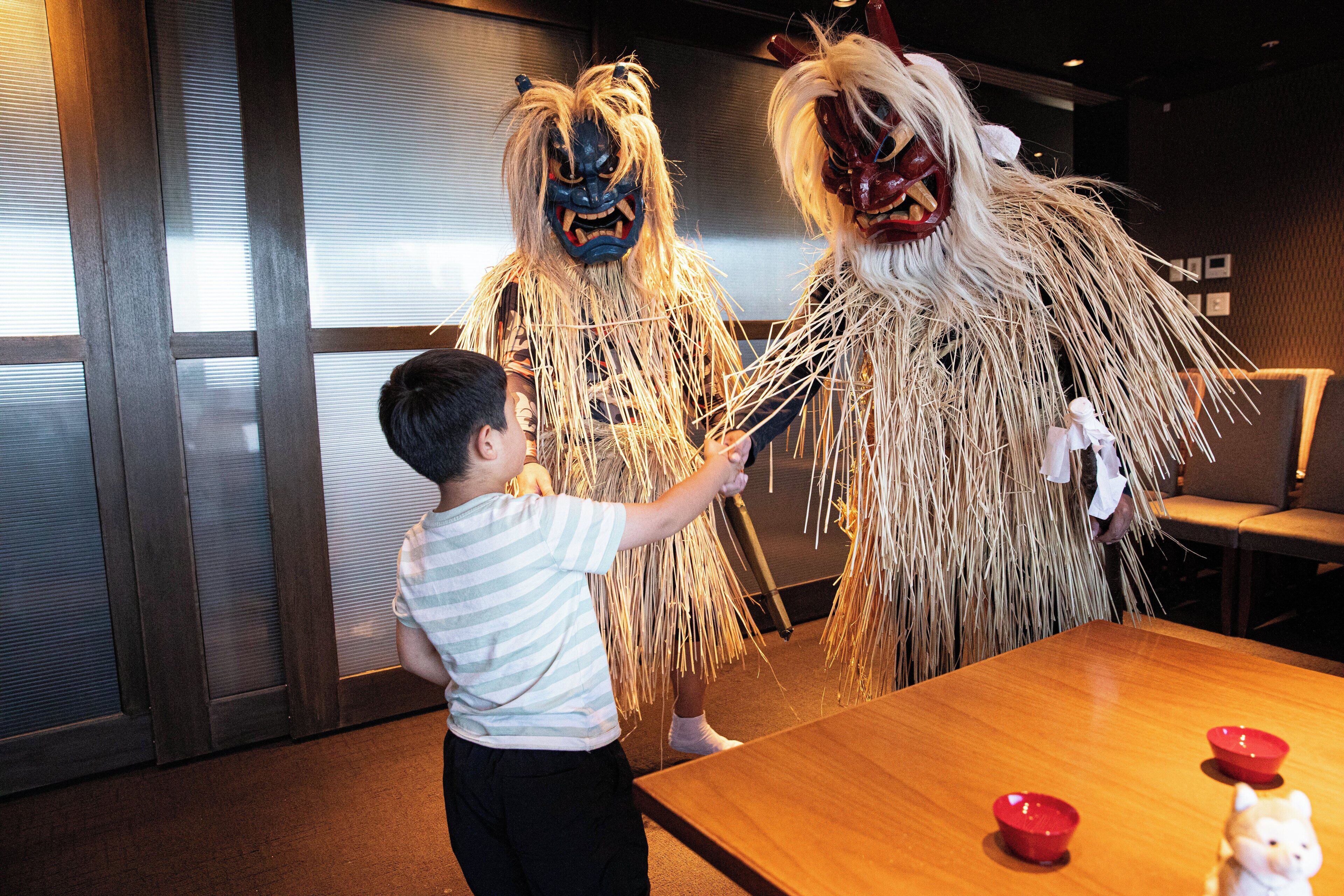 Un niño interactuando con dos personas vestidas con trajes tradicionales.