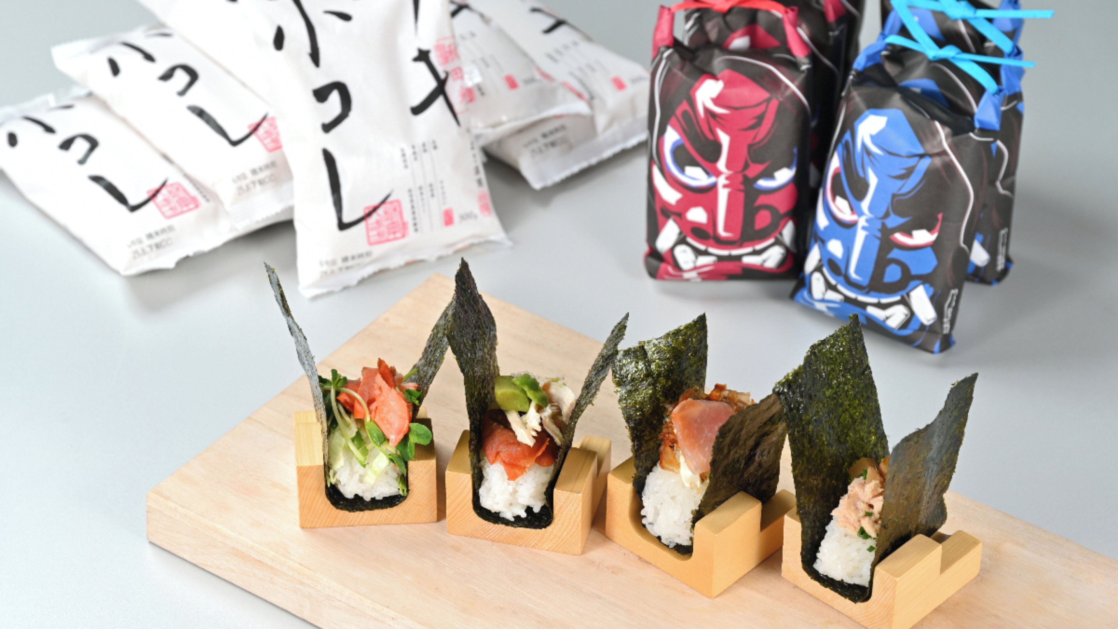 Sushi rolls on wooden blocks with seaweed on top, arranged on a wooden board.