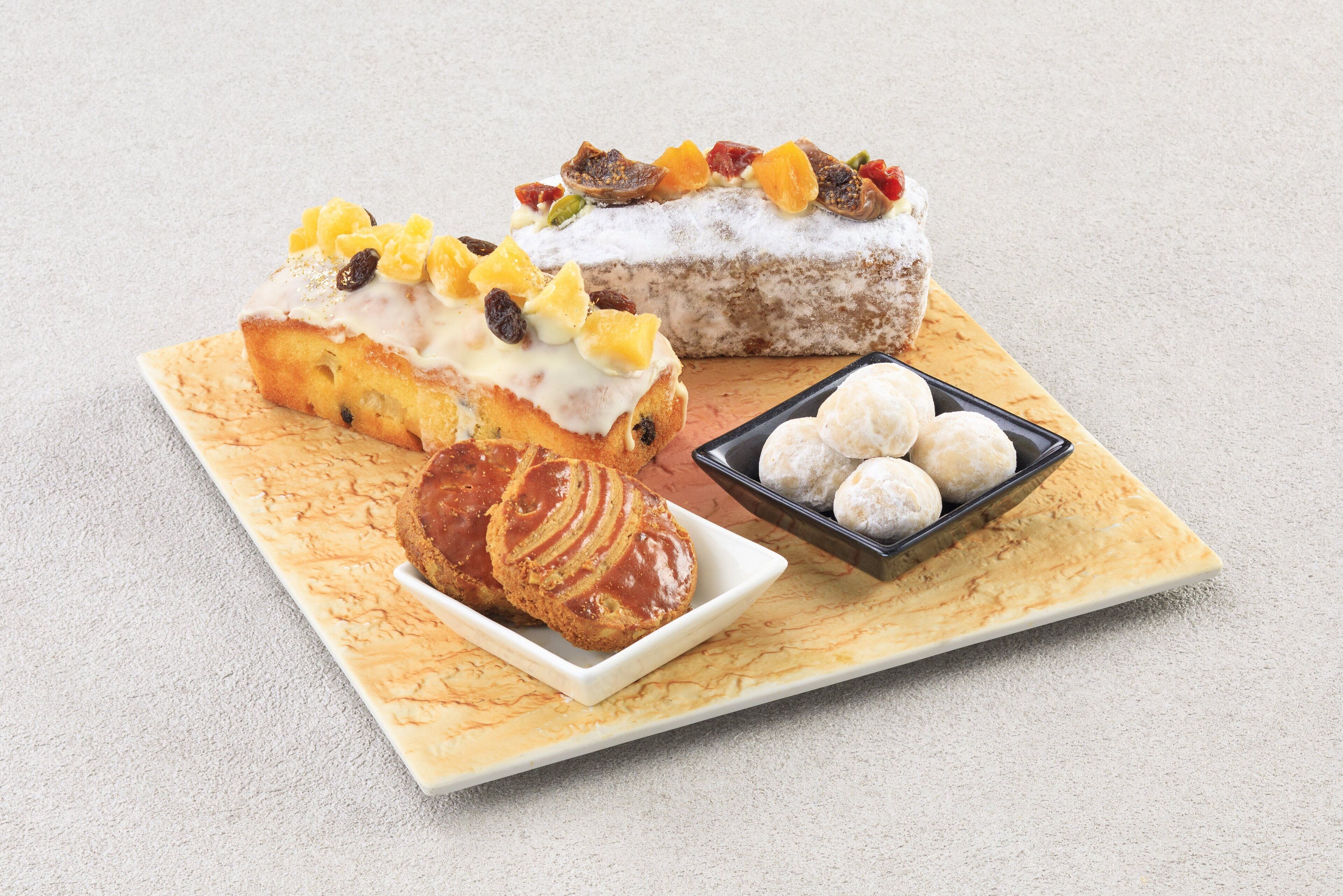 A dessert tray with various pastries and a small bowl of round sweets.