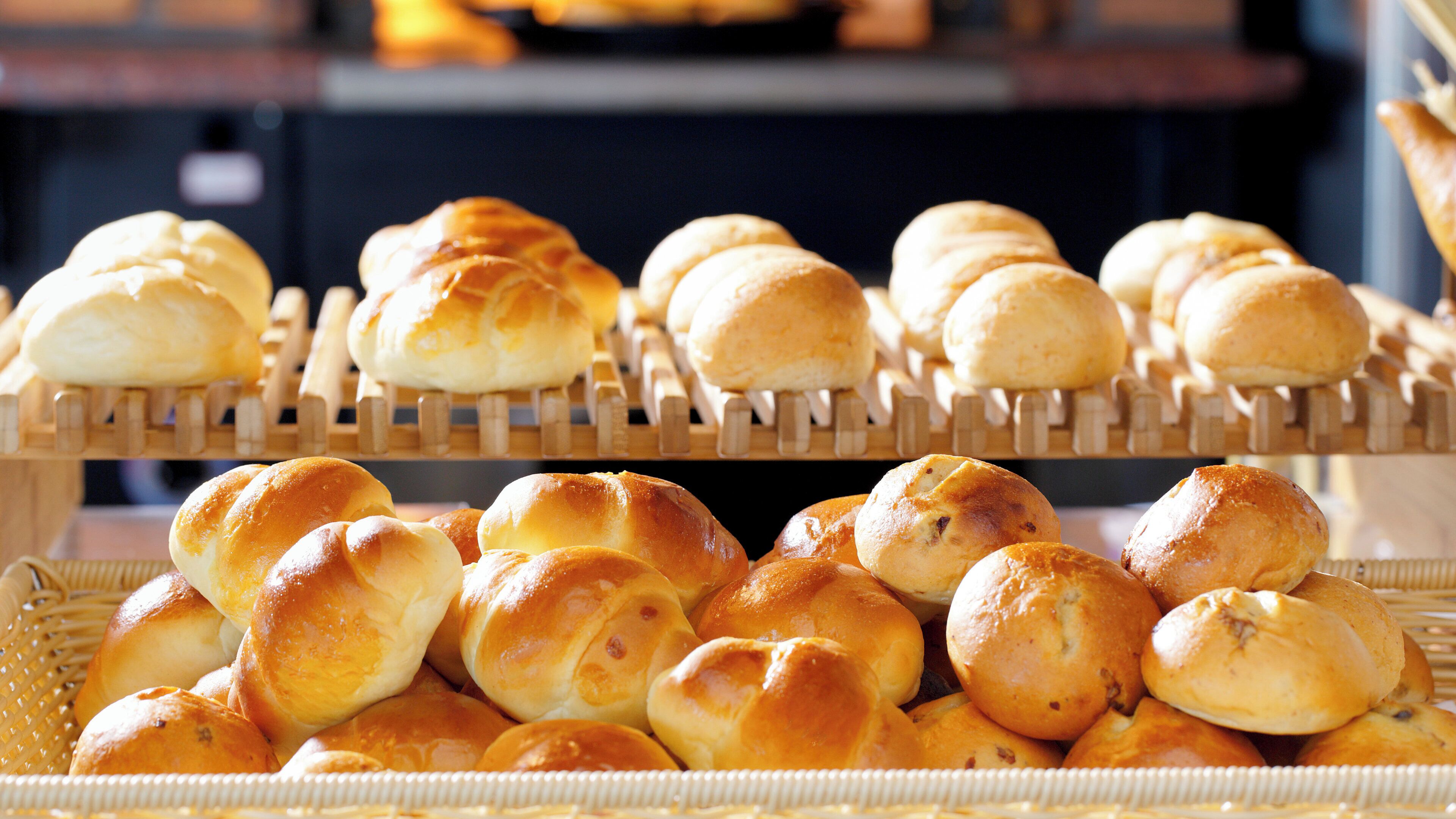 A display of various baked goods, including rolls and buns, arranged on wooden racks and baskets.