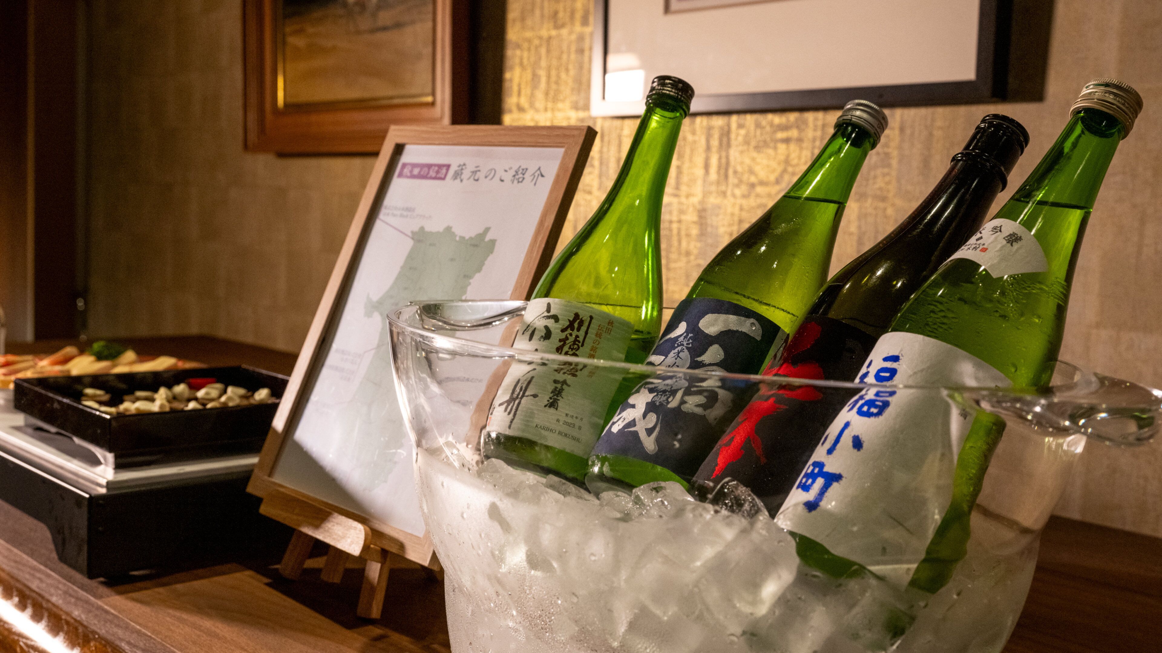A glass container filled with ice and three bottles of sake.
