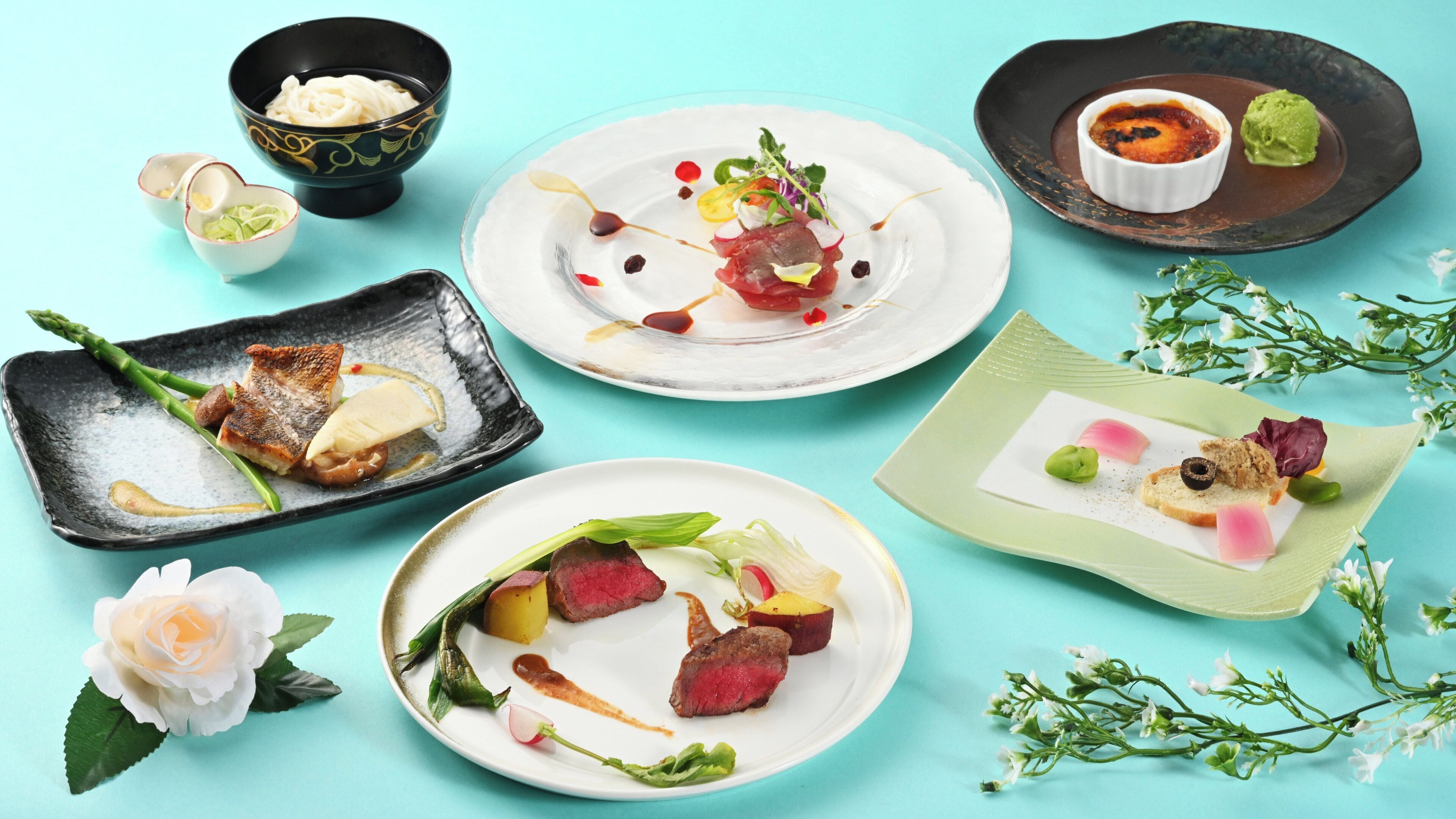 A variety of dishes on different plates, including a bowl of noodles, a plate with steak and vegetables, and a dessert with a green scoop.
