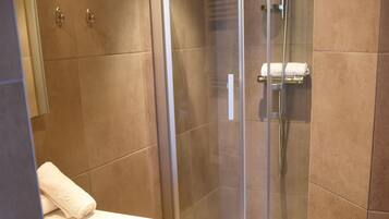 Un baño moderno con ducha envuelta en vidrio, un lavabo blanco y un mueble de madera.