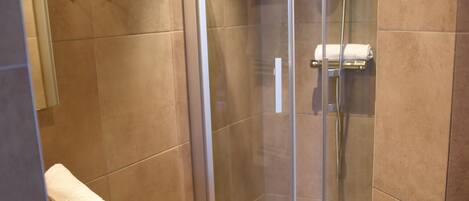 A modern bathroom with a glass-enclosed shower, a white sink, and a wooden cabinet.