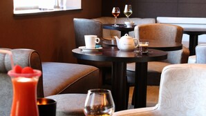 Een eetgedeelte met zachte zitting, een tafel met theepot, kopjes en glazen, en een schaal eten.