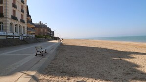 Een strand met een bankje en een gebouw met balkons.
