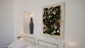 A bedroom with a bed, two bedside lamps, a wall-mounted mirror, and a floral wall decoration. - Dimora del Duca Masseria B&B (Monteroni di Lecce)