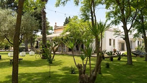 A courtyard with a white building, trees, a hammock, and outdoor seating. - Dimora del Duca Masseria B&B (Monteroni di Lecce)