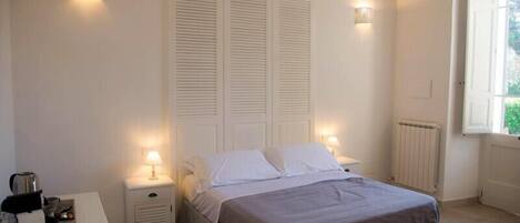 A bedroom with a bed, nightstands, a dresser, and two wall-mounted lamps.