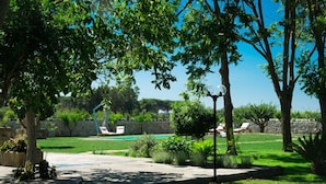 A well-maintained garden with a swimming pool, lounge chairs, and a lamp post. - Dimora del Duca Masseria B&B (Monteroni di Lecce)