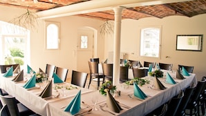 Un espace repas avec des tables rondes dressées pour le service, agrémenté de chaises foncées et de serviettes de couleur turquoise.