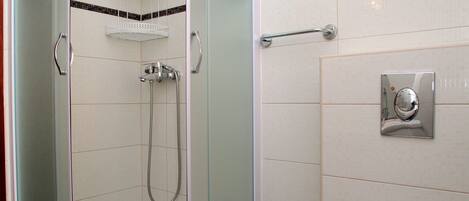 A bathroom with a glass-enclosed shower, a white toilet, and a tiled floor.
