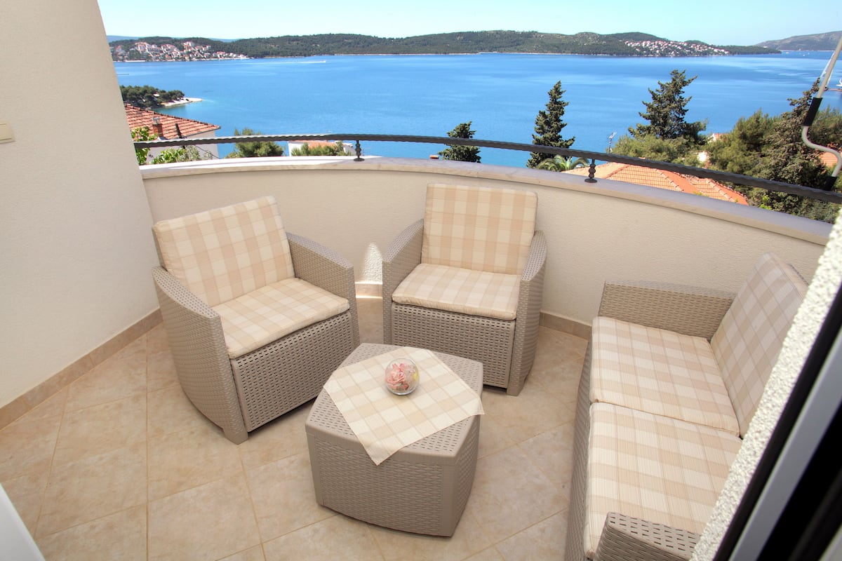 A balcony with wicker furniture and a view of the sea.