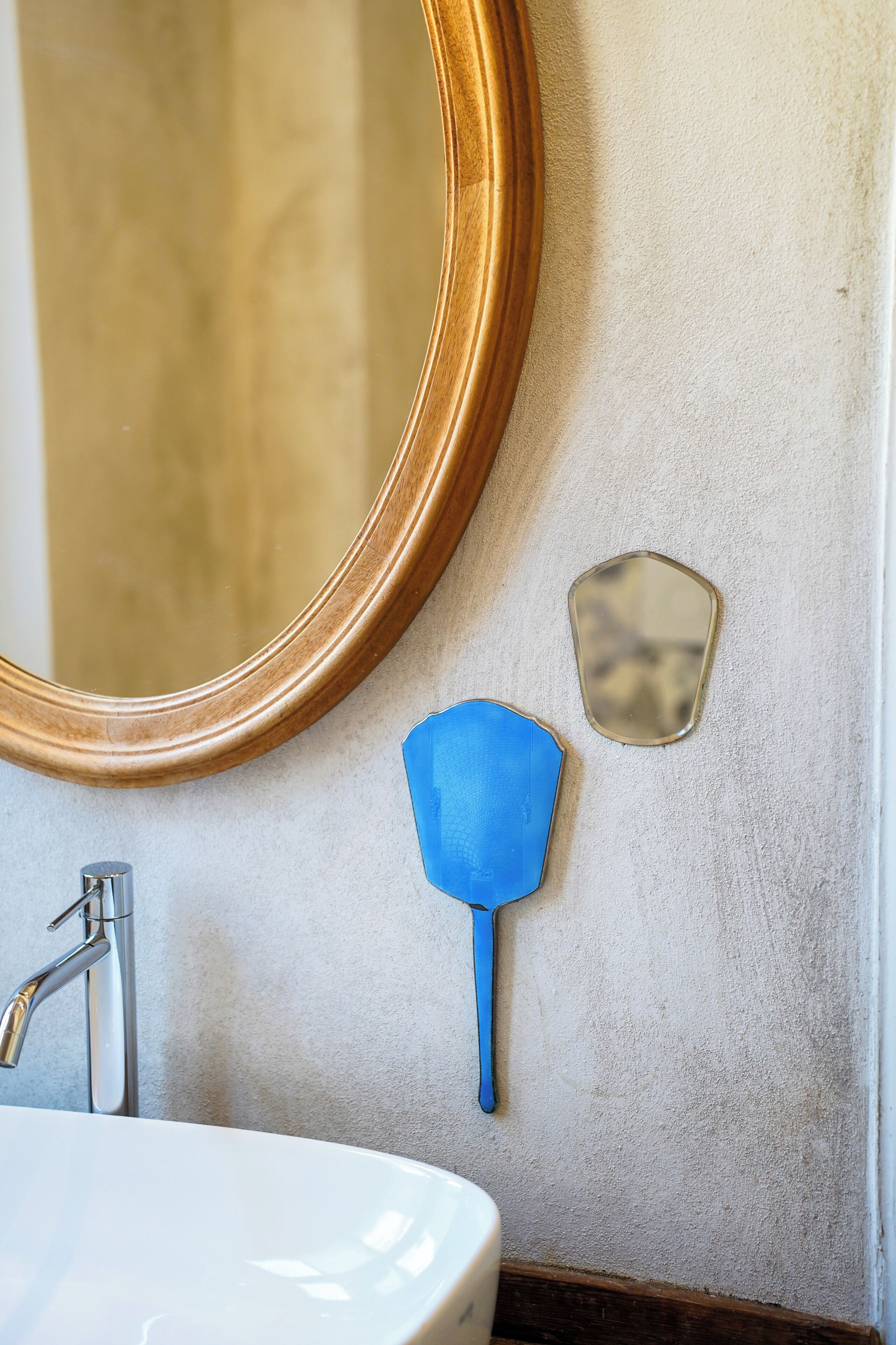 A bathroom with a white sink, a mirror, and a blue handheld fan.