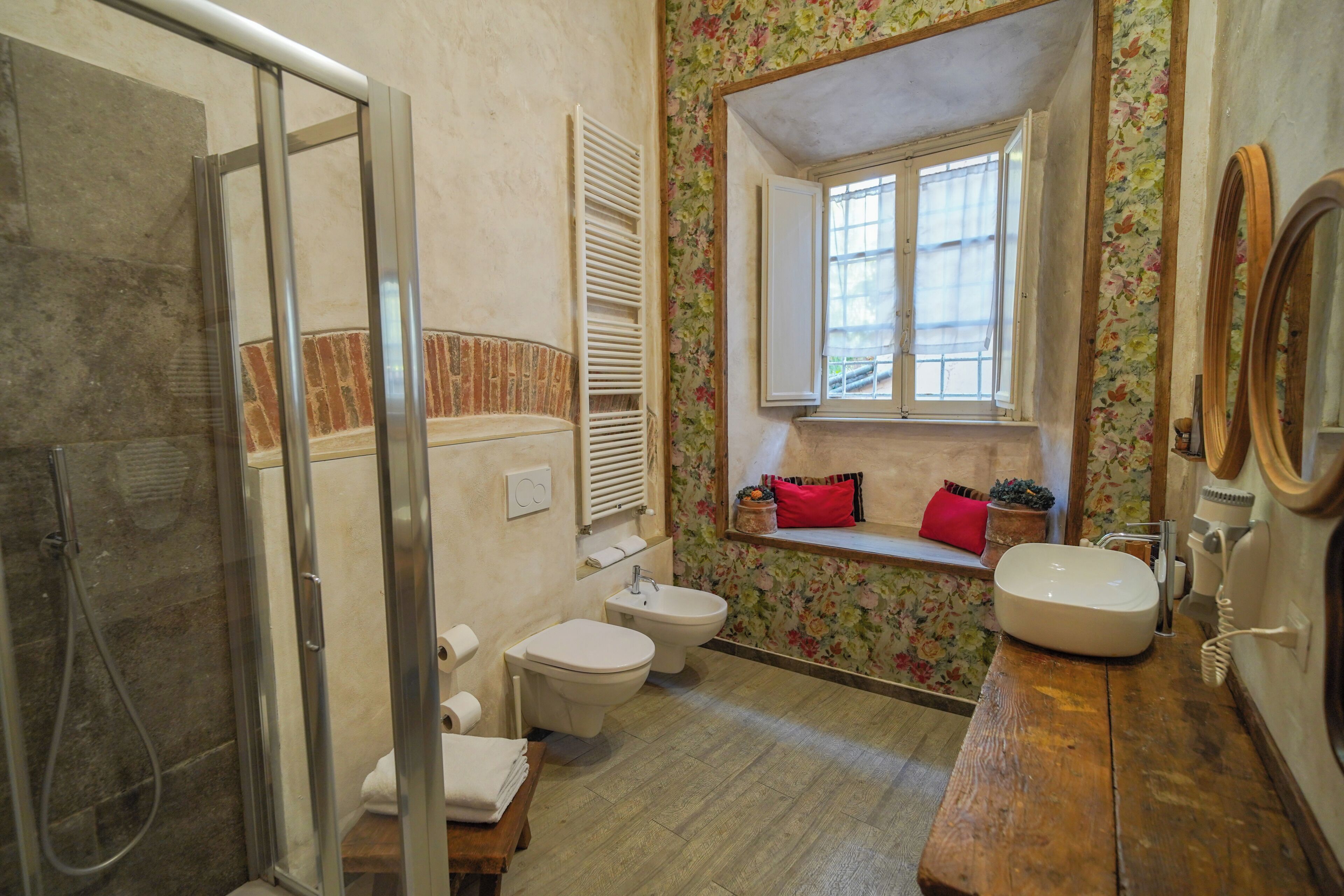 Un baño con ducha, inodoro, bidé, lavabo y ventana con vistas.