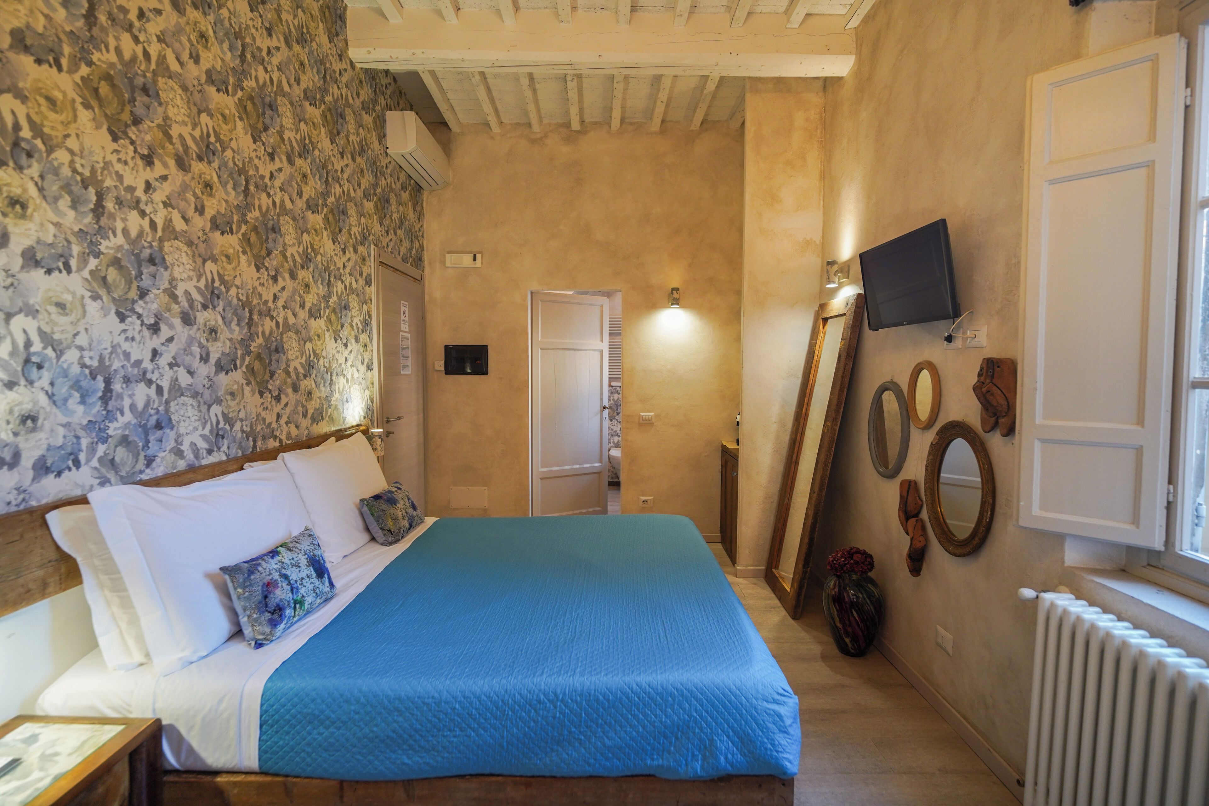 Un dormitorio con una cama, televisión, espejo y radiador.