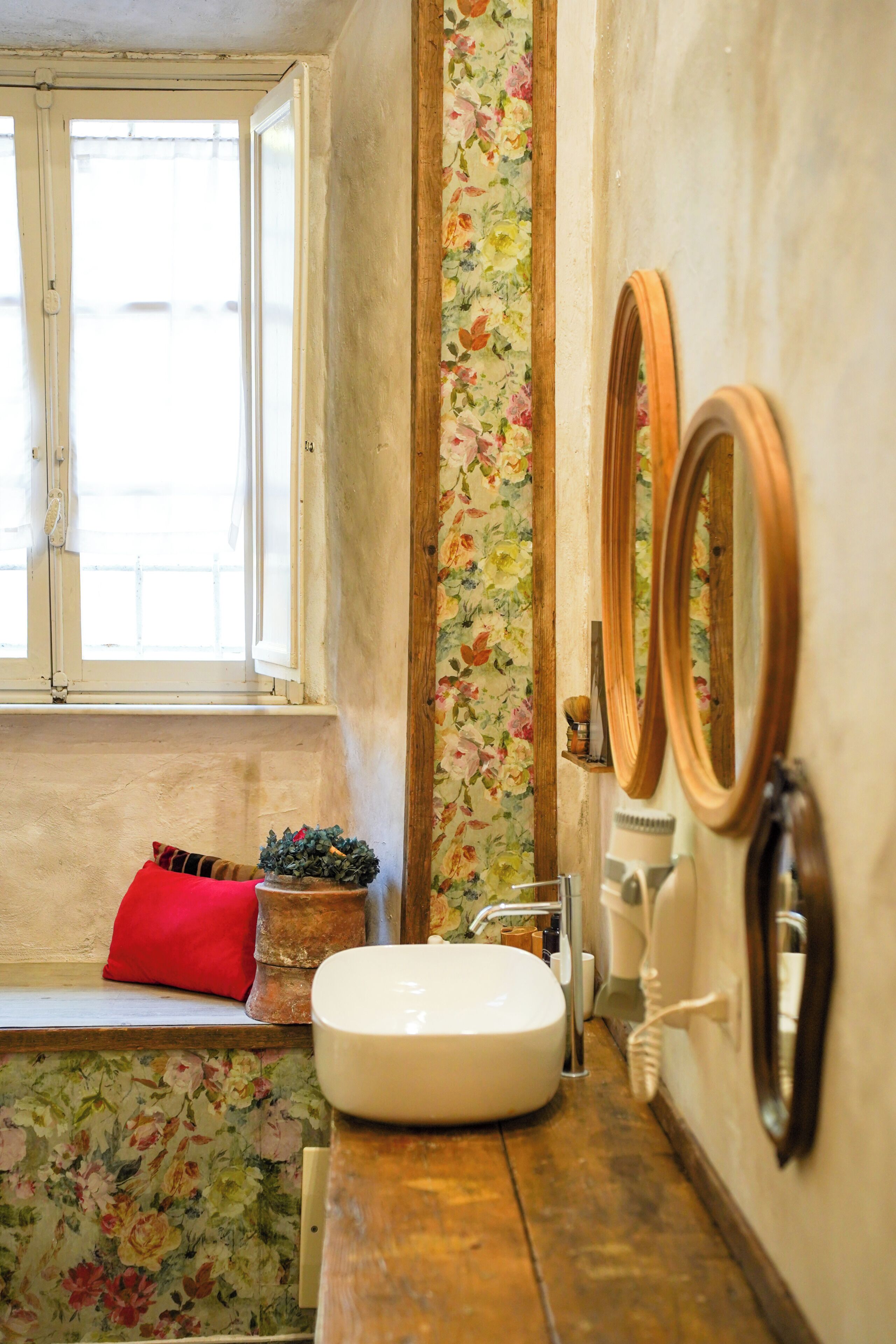 A bathroom with a window, a sink, and two mirrors.