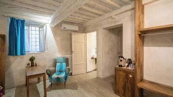 Una habitación con techo de madera, una ventana con cortinas azules, un radiador, un armario de madera y una silla.
