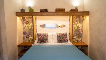 Ein Schlafzimmer mit einem Bett, floralem Wandpapier, einem Holzkopfende und Nachttischen.