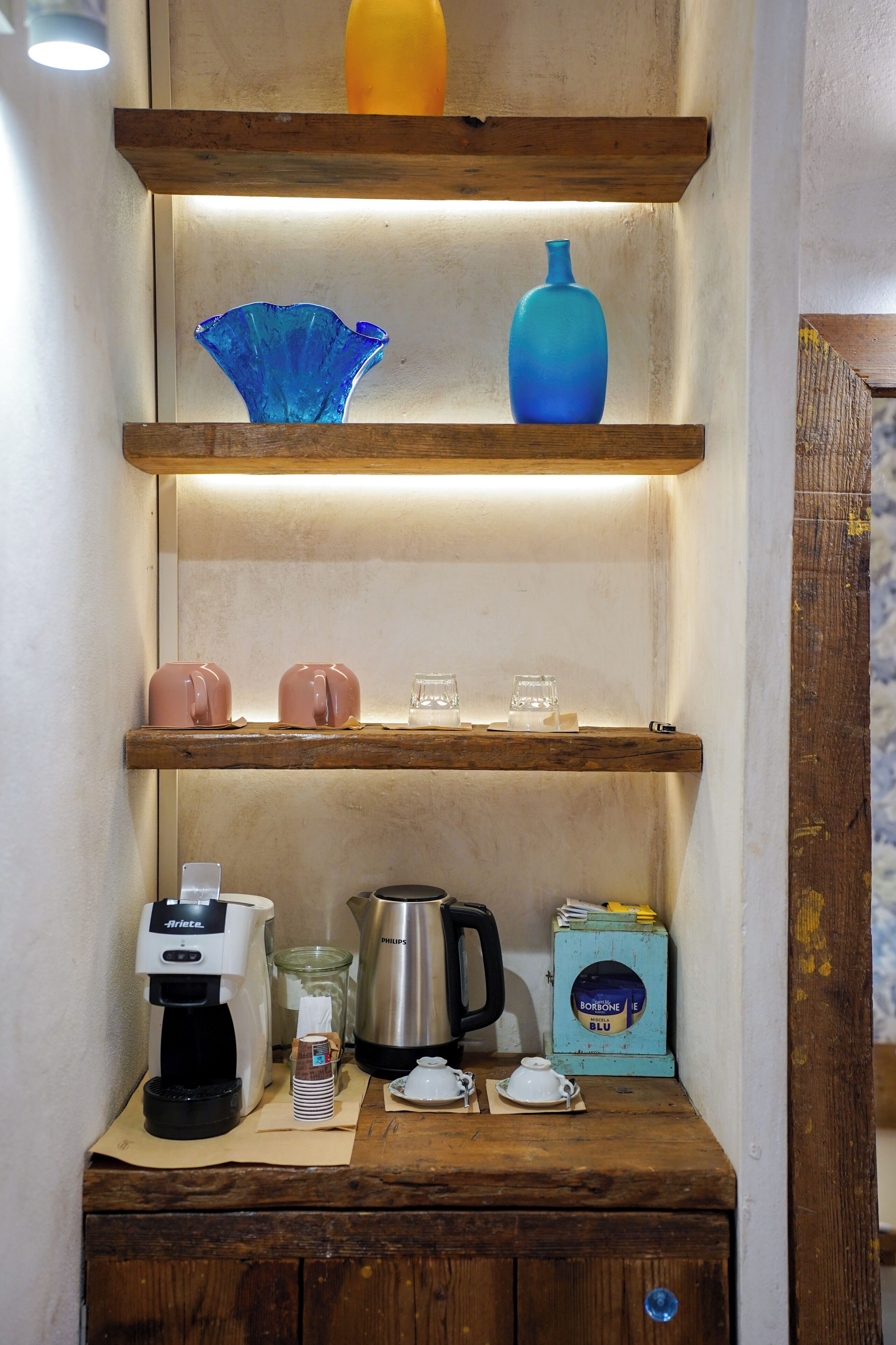 A wooden shelf with decorative vases, a coffee maker, a kettle, and a box labeled 'Borelle Blu'.