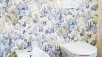 Un baño con bidé, inodoro y pared con papel tapiz floral.