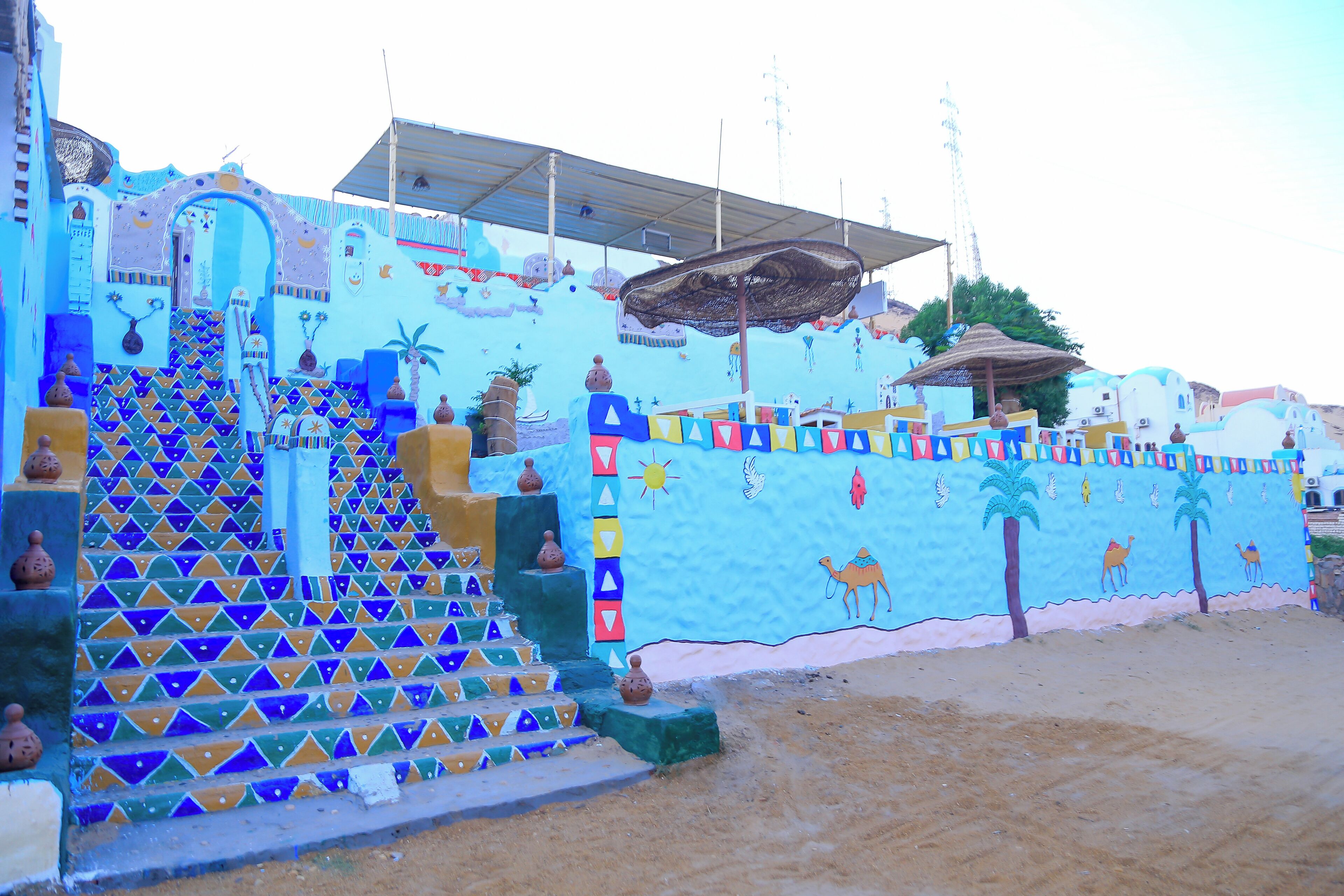 A colorful building with a staircase leading to a door, decorated with geometric patterns and small vases.