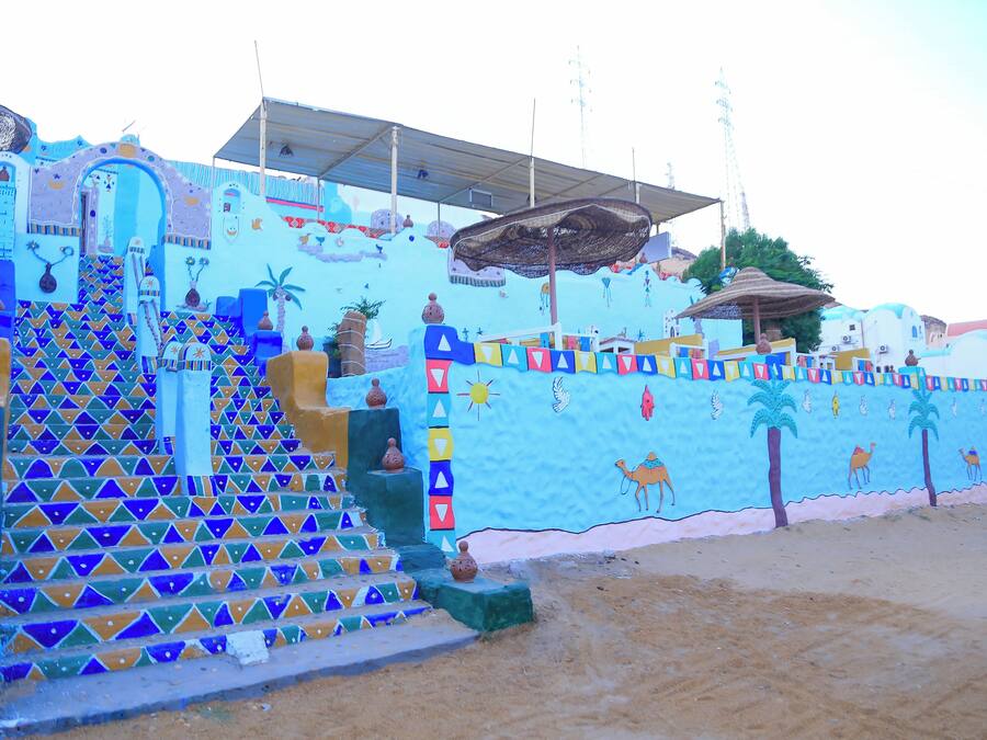 A colorful building with a staircase leading to a door, decorated with geometric patterns and small vases.