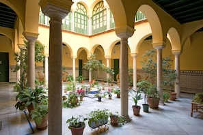 A courtyard with arches, columns, and potted plants. - Botanic Duplex Private Terrace 6 pax next to Cathedral (SEVILLA)