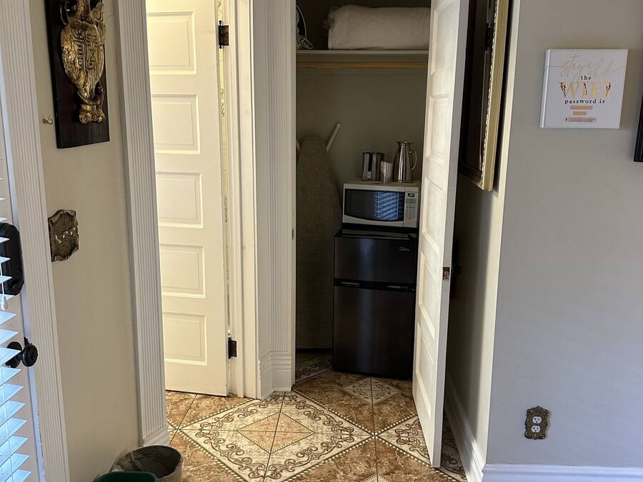 Un pasillo con una zona de cocina, que incluye un microondas, un refrigerador y armarios.
