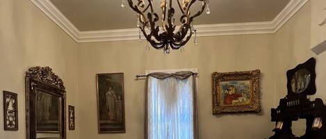A formal dining room with a chandelier, a piano, and framed artwork on the walls.