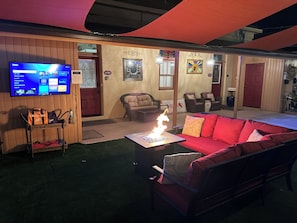 A cozy living room with a red sofa, a TV mounted on the wall, and a small fire feature. - El Amador Inn Downtown Tucson (Tucson)
