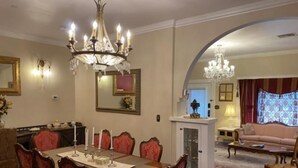 A dining area with a chandelier, a dining table set for six, and red upholstered chairs. - El Amador Inn Downtown Tucson (Tucson)