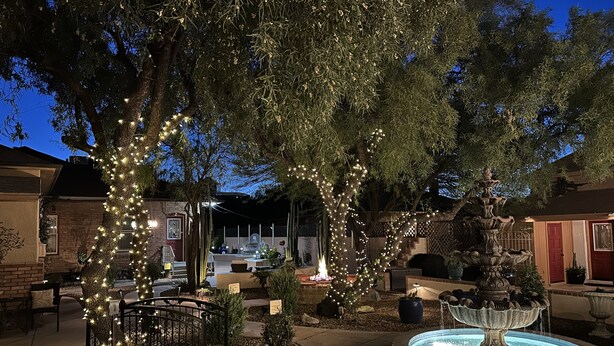 A courtyard with a fountain, trees wrapped in lights, and a brick building in the background. - El Amador Inn Downtown Tucson (Tucson)