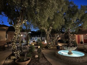 A courtyard with a fountain, trees wrapped in lights, and a brick building in the background. - El Amador Inn Downtown Tucson (Tucson)
