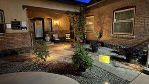A courtyard with outdoor seating, a brick building, and a sign indicating a quiet hours policy. - El Amador Inn Downtown Tucson (Tucson)