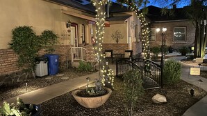 A courtyard with a brick building, outdoor seating, and decorative lights. - El Amador Inn Downtown Tucson (Tucson)