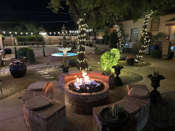 An outdoor patio area with a fire pit, seating, a fountain, and string lights. - El Amador Inn Downtown Tucson (Tucson)