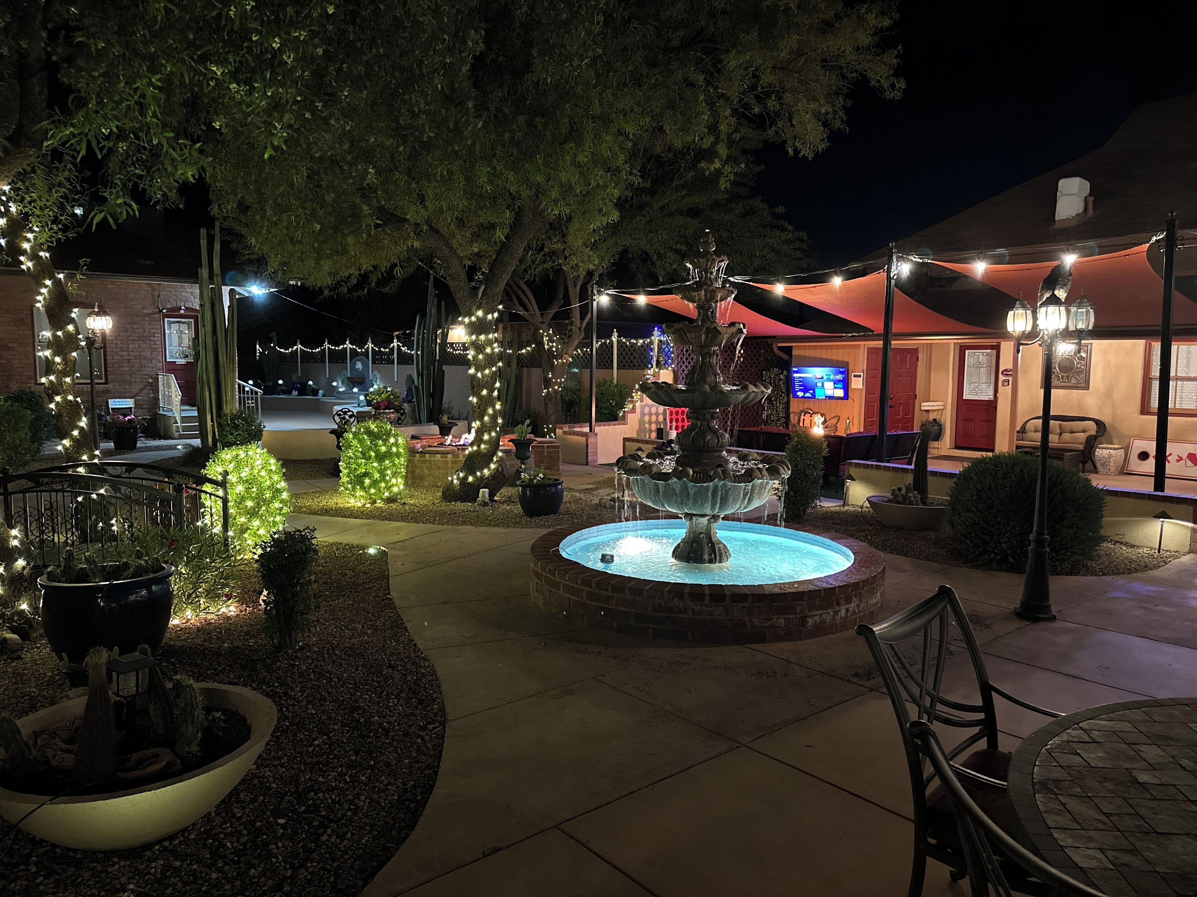 A courtyard with a fountain, potted plants, and string lights.